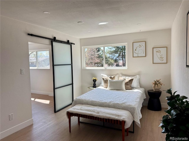 bedroom featuring a barn door, baseboards, and wood finished floors