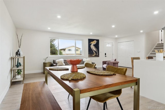 dining area with light wood-type flooring, stairway, baseboards, and recessed lighting