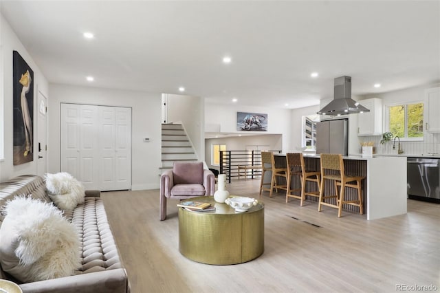living area with light wood finished floors, stairway, and recessed lighting