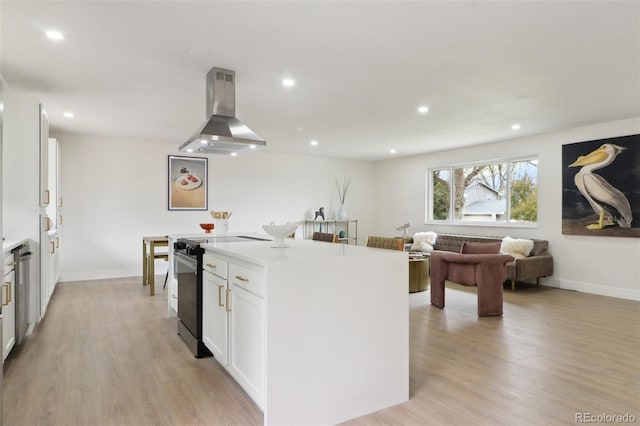 kitchen featuring light wood-style flooring, island range hood, white cabinets, electric range oven, and a kitchen island