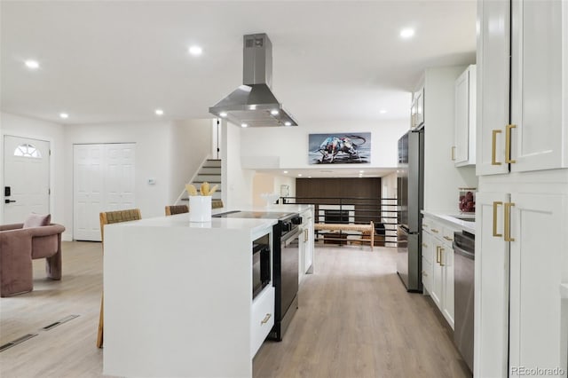 kitchen featuring recessed lighting, island exhaust hood, open floor plan, stainless steel appliances, and white cabinets