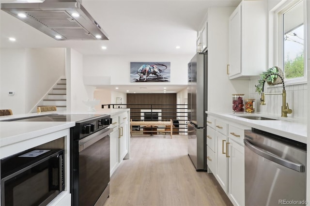 kitchen featuring light wood-style floors, custom exhaust hood, white cabinets, and appliances with stainless steel finishes