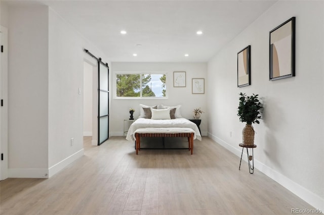 bedroom with light wood-type flooring, a barn door, baseboards, and recessed lighting