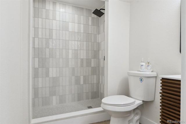 bathroom featuring toilet, a tile shower, and vanity