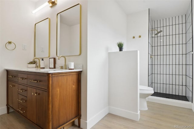 bathroom with vanity, a walk in shower, baseboards, and wood finished floors