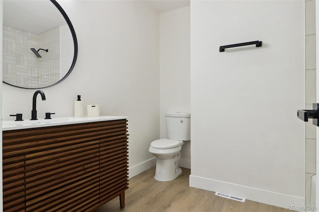 full bath with toilet, wood finished floors, visible vents, baseboards, and vanity