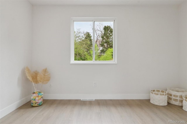 spare room featuring baseboards, visible vents, and wood finished floors