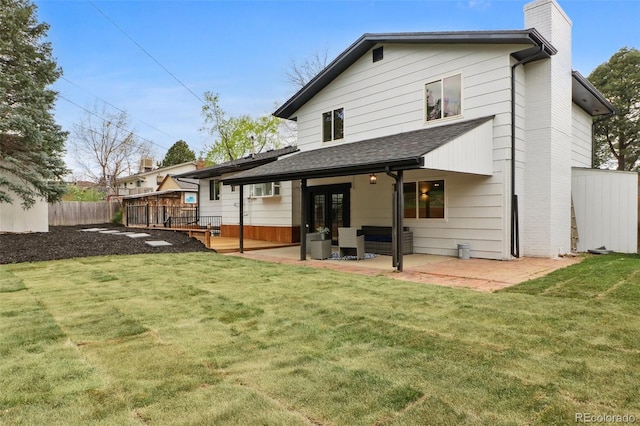 rear view of house featuring a chimney, a wooden deck, fence, a yard, and a patio area
