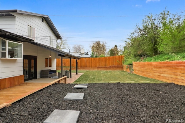 view of yard featuring a fenced backyard, a wooden deck, and french doors