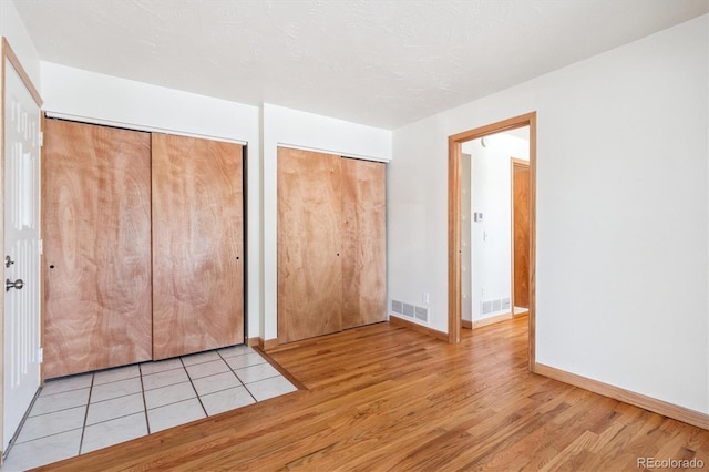 4656 S Dillon Ct Unit D, Aurora, CO 80015 - unfurnished bedroom featuring light wood-style flooring and multiple closets