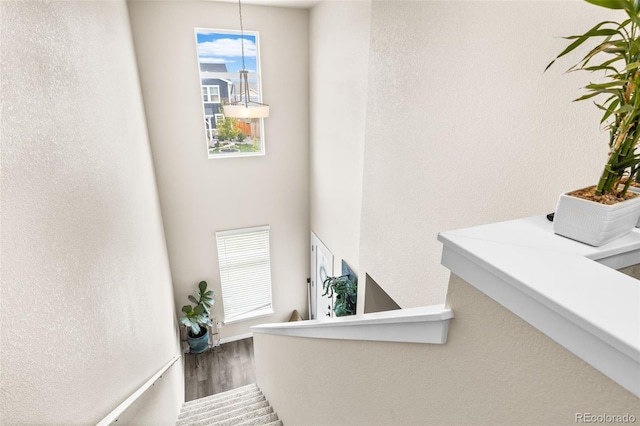 stairway with visible vents, a textured wall, and wood finished floors