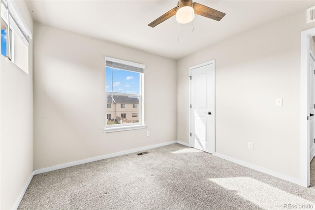 unfurnished room with visible vents, baseboards, carpet, and a ceiling fan