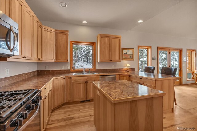 kitchen with a peninsula, recessed lighting, a sink, light wood-style flooring, and appliances with stainless steel finishes