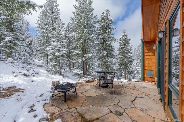 snow covered patio featuring an outdoor fire pit