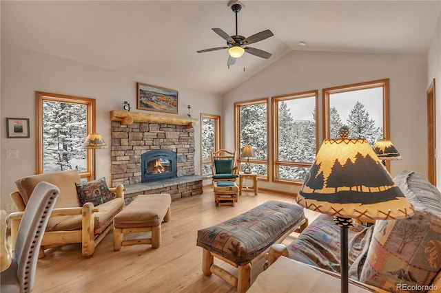living room with a stone fireplace, a ceiling fan, wood finished floors, and vaulted ceiling