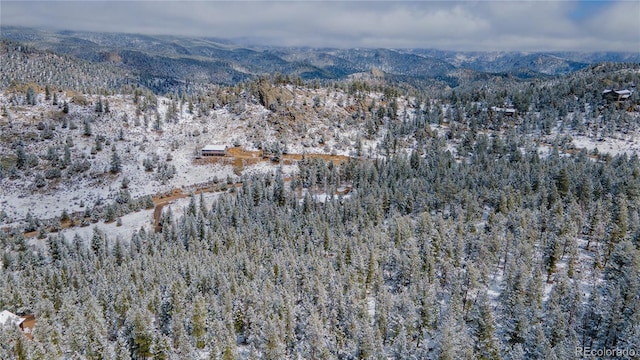 snowy aerial view featuring a view of trees and a mountain view
