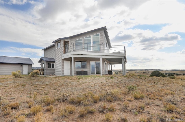 back of property featuring a balcony and central AC