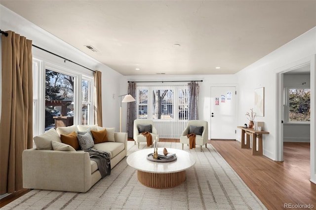 living room with visible vents, wood finished floors, a wealth of natural light, and baseboards