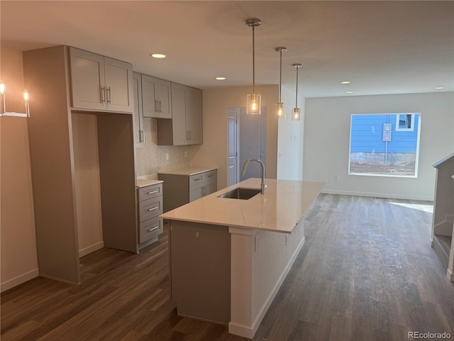 kitchen with tasteful backsplash, baseboards, dark wood finished floors, gray cabinetry, and a sink