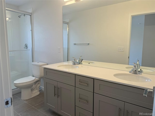 bathroom with toilet, a shower stall, double vanity, and a sink