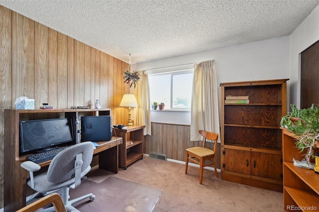 office space with wooden walls, a textured ceiling, visible vents, and carpet