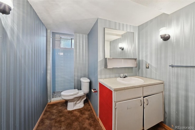 bathroom featuring vanity, toilet, baseboards, wallpapered walls, and a stall shower