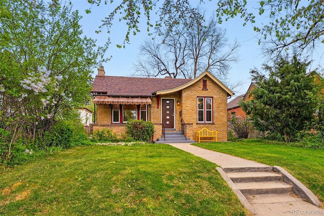 bungalow featuring brick siding, a front lawn, and a chimney