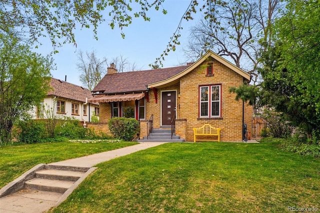 view of front of property featuring a chimney, a front lawn, and brick siding