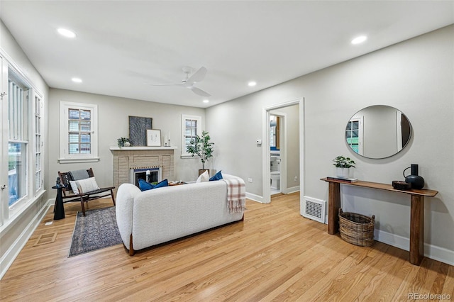 living area featuring visible vents, a fireplace, baseboards, recessed lighting, and light wood finished floors