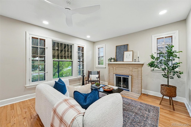 living area featuring a fireplace, recessed lighting, baseboards, a ceiling fan, and light wood-type flooring