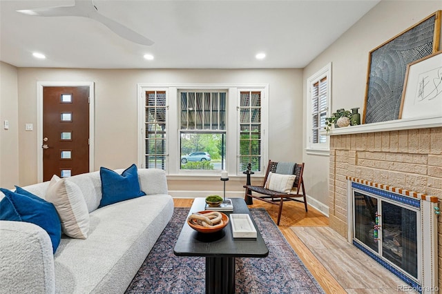 living room featuring a brick fireplace, wood finished floors, baseboards, recessed lighting, and a ceiling fan