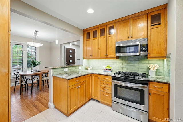 kitchen featuring backsplash, light stone countertops, a peninsula, glass insert cabinets, and stainless steel appliances