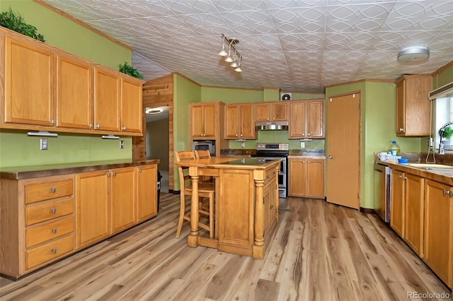 kitchen with a center island, vaulted ceiling, appliances with stainless steel finishes, light hardwood / wood-style floors, and a kitchen bar