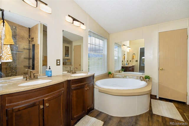 bathroom with a textured ceiling, vanity, hardwood / wood-style flooring, and plus walk in shower