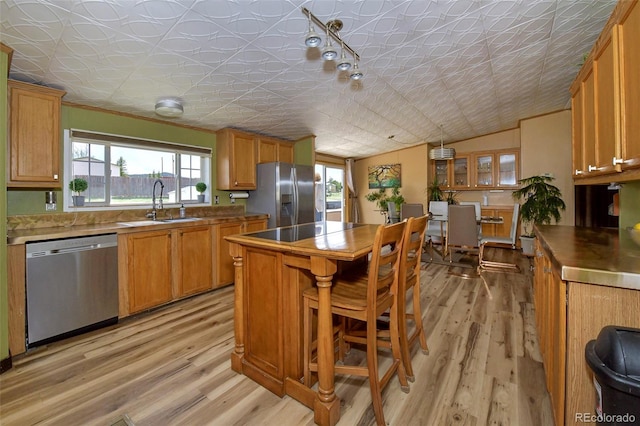 kitchen featuring a wealth of natural light, a kitchen bar, stainless steel appliances, and light hardwood / wood-style floors