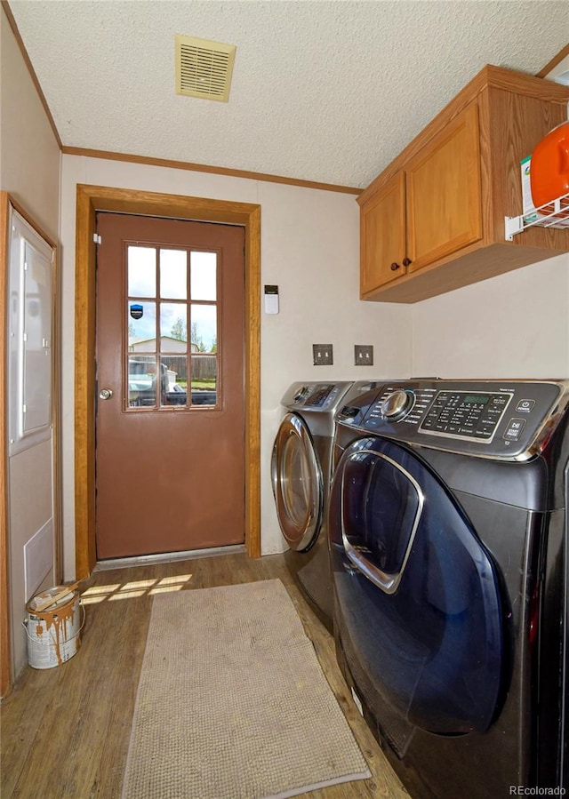 washroom featuring washer and dryer, a textured ceiling, cabinets, and light hardwood / wood-style flooring