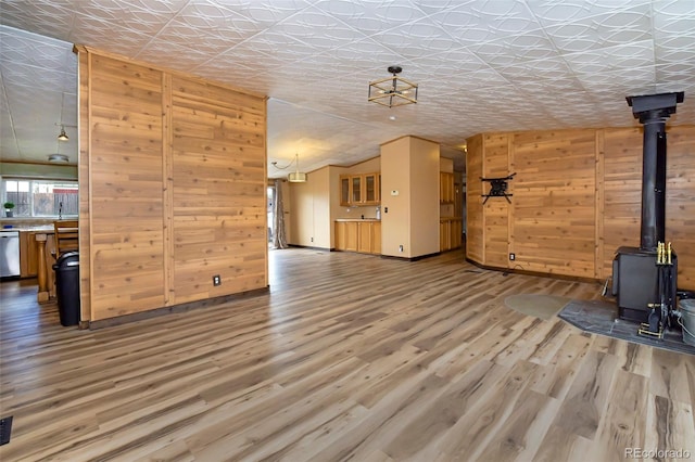 unfurnished living room with a wood stove, wood walls, and hardwood / wood-style floors