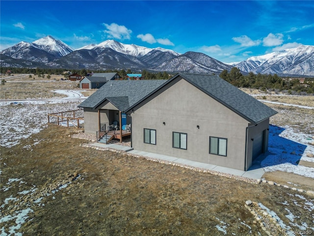 snow covered back of property featuring a mountain view