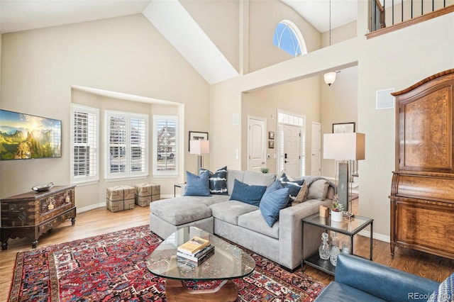 living area with high vaulted ceiling, baseboards, and wood finished floors