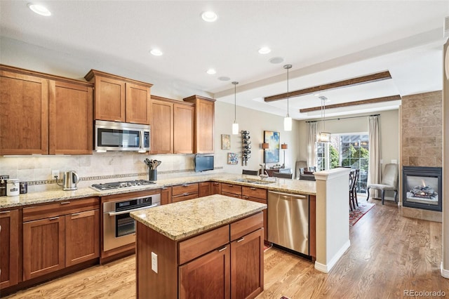 kitchen with tasteful backsplash, appliances with stainless steel finishes, brown cabinets, a peninsula, and light wood-type flooring