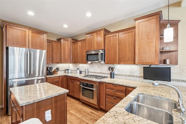 kitchen featuring appliances with stainless steel finishes, a sink, light stone counters, and tasteful backsplash