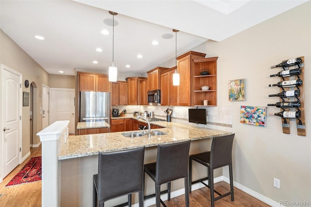 kitchen featuring a peninsula, a sink, appliances with stainless steel finishes, decorative backsplash, and open shelves