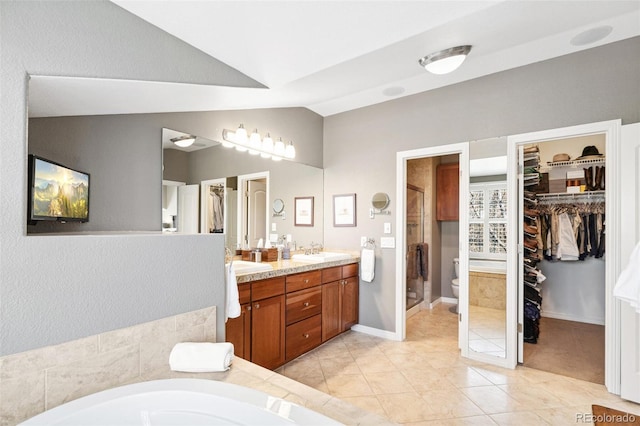 bathroom featuring tile patterned flooring, a sink, vaulted ceiling, a shower stall, and double vanity