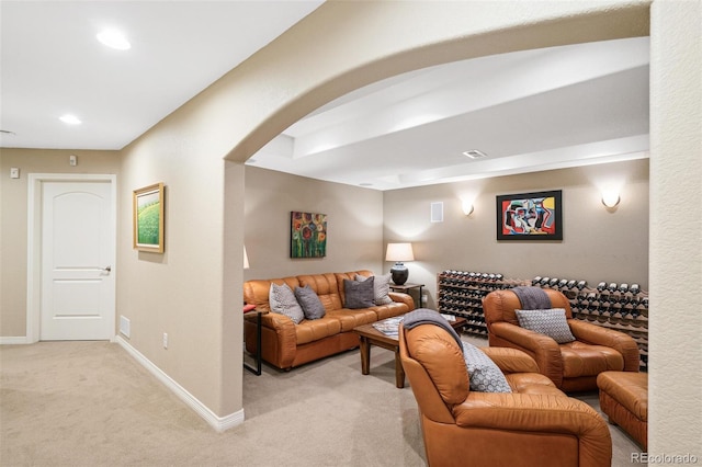 living area featuring light carpet, visible vents, baseboards, arched walkways, and recessed lighting