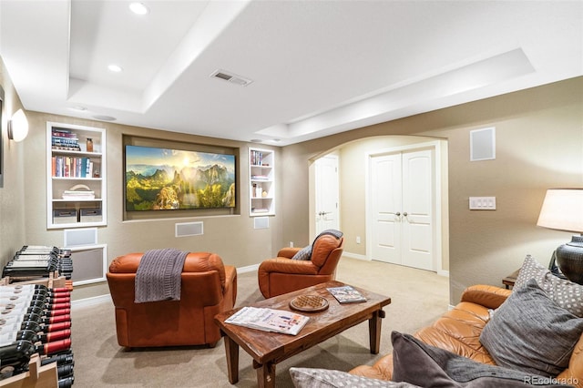 cinema with visible vents, built in shelves, a tray ceiling, and arched walkways