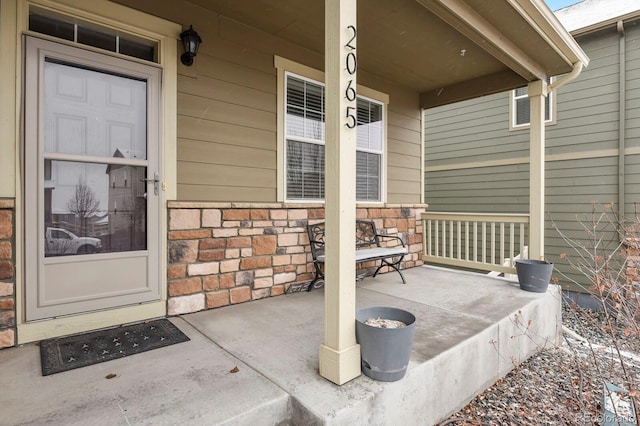 entrance to property featuring stone siding and covered porch