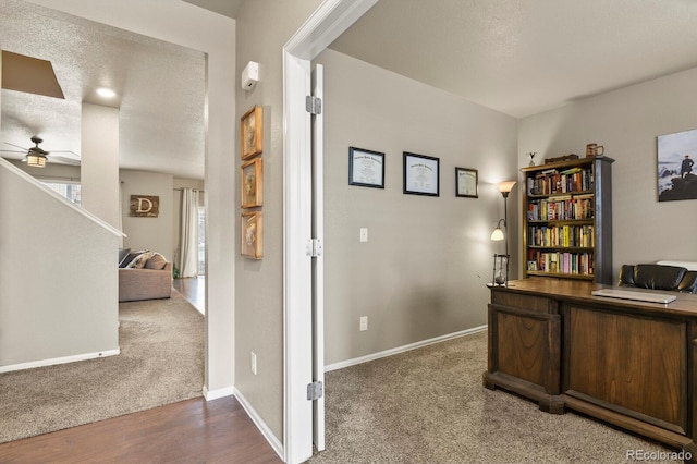 office space featuring a textured ceiling, wood finished floors, carpet, baseboards, and ceiling fan