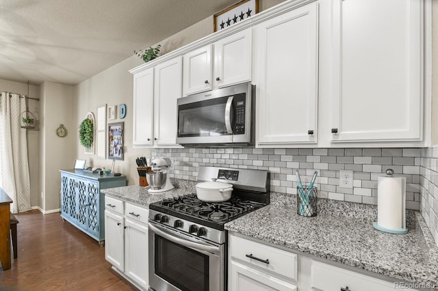 kitchen with white cabinetry, dark wood-type flooring, backsplash, and stainless steel appliances