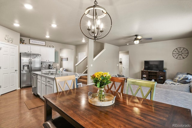 dining area featuring stairs, ceiling fan with notable chandelier, recessed lighting, and dark wood finished floors