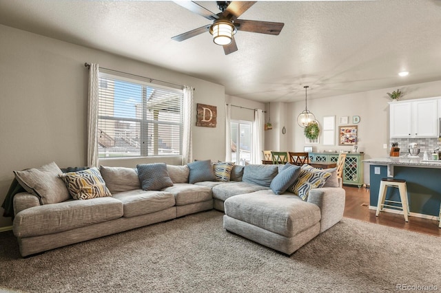 living room featuring a textured ceiling, a ceiling fan, and dark wood-style flooring